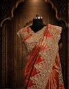 Portrait view of the rust saree blouse showcasing intricate golden zari, sequence lines, and fine kardana embroidery on the neckline.