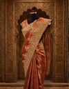 Elegant back profile of the rust tissue saree look showing its graceful pleats, fluid drape, and the stylish tie-up design of the matching blouse.