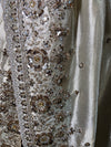 A macro close-up of the border detailing the precise hand-placement of golden cut beads and metallic sequins clustered into ornate rosettes.