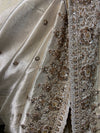 A detailed textile texture shot showing the high-sheen weave of the Tissue silk, contrasted against rows of shimmering manual embroidery and fine scalloped edging.