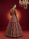 Back profile of a red color bridal lehenga showing a heavily embroidered blouse and sheer silk dupatta.
