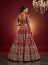 Back profile of a red color bridal lehenga showing a heavily embroidered blouse and silk dupatta.