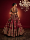 Back profile of the maroon bridal lehenga highlighting the expansive raw silk skirt and the intricate craftsmanship of the bridal blouse.