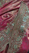 Close-up macro shot of the fuchsia tissue fabric highlighting the detailed hand-woven gold zari patterns and tiny white pearl accents.
