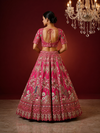 Close-up of a pink silk lehenga featuring a detailed peacock motif and birdcage design crafted with white pearls and gold zardozi.