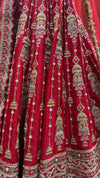 Close-up of a red color lehenga showing detailed vertical embroidery lines featuring bell and temple motifs with white pearls.