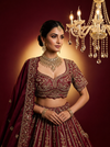 Close-up of maroon raw silk fabric featuring dense gold zardozi embroidery and delicate white pearl accents.