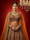 Close-up of rust tissue lehenga featuring intricate manual embroidery with cut beads and zari work.
