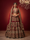 Full-length front view of a bride in a cherry red silk lehenga choli with heavy gold embroidery and a matching net dupatta.