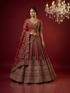 Full-length front view of a model in a cherry red lehenga choli with heavy gold zari and stone work under a luxury chandelier.