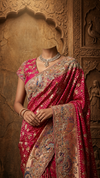 Full-length front view of a model showcasing a voluminous rani pink georgette saree with traditional bandhani prints and dense gold zari borders under a crystal chandelier.