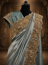 A three-quarter studio presentation on a mannequin highlighting the heavily embellished scalloped border, showing fine gold threadwork layered with pearls and a matching sea green blouse.