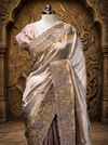 A medium portrait view of the saree on a mannequin against a highly decorative sandstone wall backdrop, highlighting the striking transition between the smooth mauve body and the gold-toned embroidered border panels.