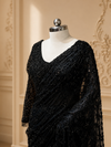 A side-angle portrait focusing on the sheer elegance of the net fabric, showing how the black sequins catch the soft ambient room lighting over the upper bodice.