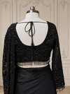 A front-facing medium shot highlighting the structured V-neckline of the matching black embroidered blouse and the rich texture of the pleated pallu neatly resting over the mannequin's shoulder.
