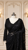 A detailed back view of the mannequin highlighting the heavily embellished blouse, showing the deep scooped-back neckline with a thin tie dori and a neat fringe of hanging black beads along the bottom hem.