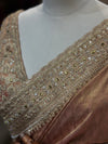 A macro texture photograph showing a soft, close-up view of the inner border and shoulder pleats, revealing the precision placement of sparkling stones and gold thread lining.

