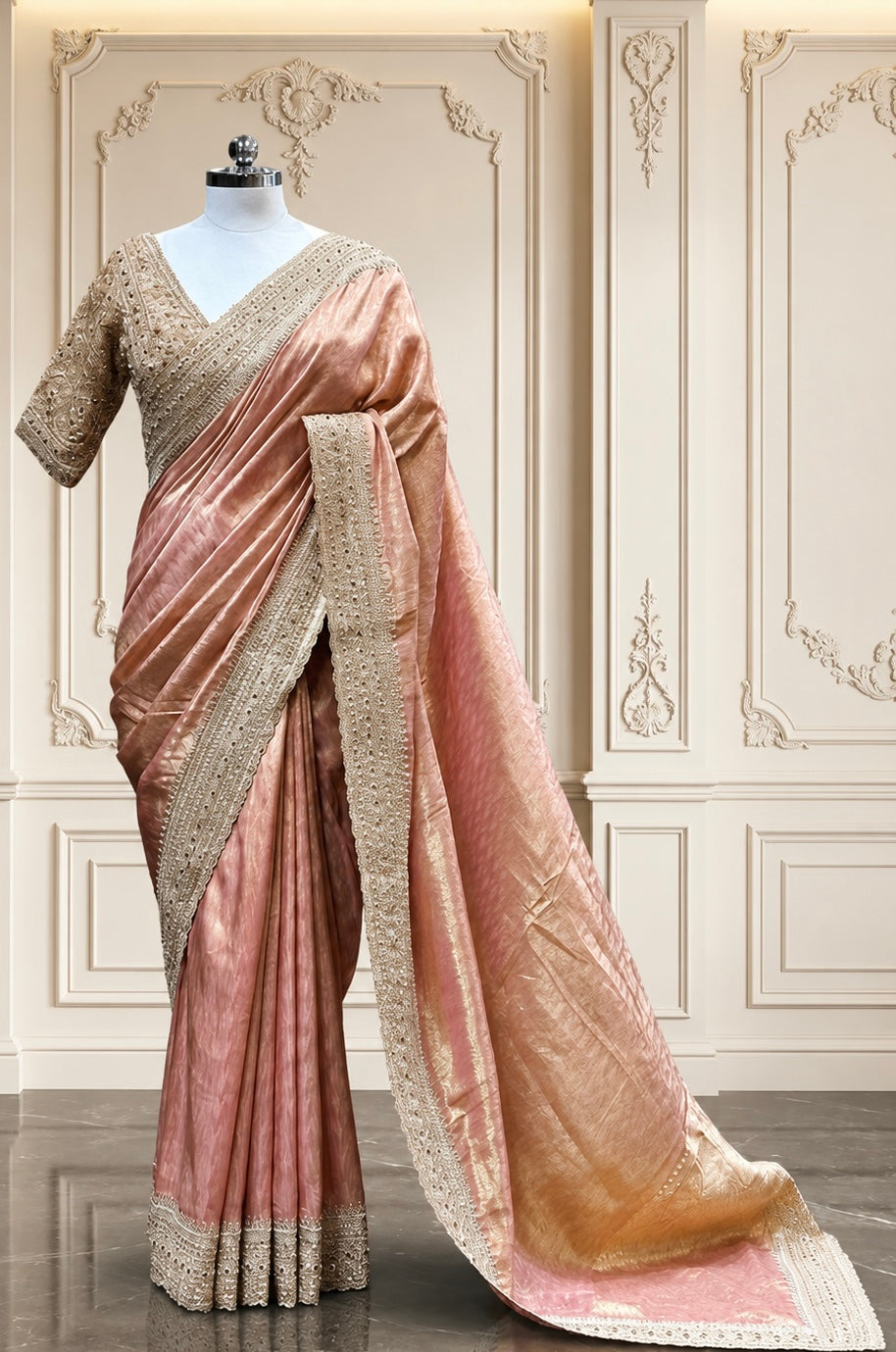 A grand full-length view of the peach tissue silk saree draped gracefully on a mannequin, showcasing its premium golden-metallic sheen and detailed scalloped pallu against a classic cream interior wall with elegant moldings.