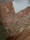 A close-up shot capturing the heavy craftsmanship of the saree pleats and shoulder border, detailing the densely patterned zari and stone embellishments layered over a rich red base.