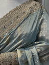 A detailed shot capturing the fluid drapes of the saree body, illustrating the subtle woven chevron stripes and floating bootis against the high-shine firozi fabric.