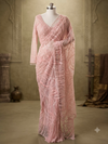 Full-length display of the blush pink net saree on a mannequin, showcasing the graceful sheer drape, all-over floral jaal pattern, and matching embellished blouse.