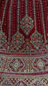 Macro shot of the heavy border on the red lehenga choli, featuring traditional zari patterns and sparkling stone embellishments.
