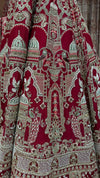Macro shot of the manual embroidery on the red silk fabric, showing high-quality cut beads, white pearls, and golden zari.