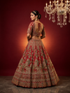 Model showcasing the heavily embellished red choli with intricate handwork and a sheer red bridal dupatta.