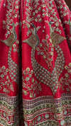 Portrait of a bride showcasing the heavily embroidered choli and the radiant red colour lehenga under warm lighting.