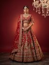Full-length front shot of a bride in a red ghagra choli with a matching dupatta and heavy traditional gold jewelry.