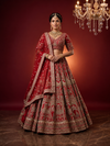 Full-length front view of a bride in a royal red bridal lehenga featuring heavy zardozi work and a matching sheer dupatta.