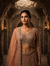 Portrait view of the model showcasing the matching peach choli with a wide square-round neckline covered in dense cut bead borders.