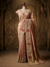 Full-length front view of a model showcasing a fluid, shimmering mauve tissue silk saree with a heavily embroidered scalloped border under a crystal chandelier.