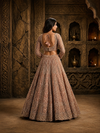 Full-length front view of a model in a voluminous peach lehenga with fine vertical cut bead lines under a decorative crystal chandelier.
