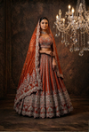 Luxury silk bridal lehenga in rust colour with intricate handwork
