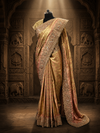 A three-quarter studio portrait of a mannequin showcasing the rust golden tissue silk saree with its heavily encrusted scalloped pallu draped neatly over the shoulder.